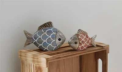 Two decorative fish figurines are placed on a wooden crate.