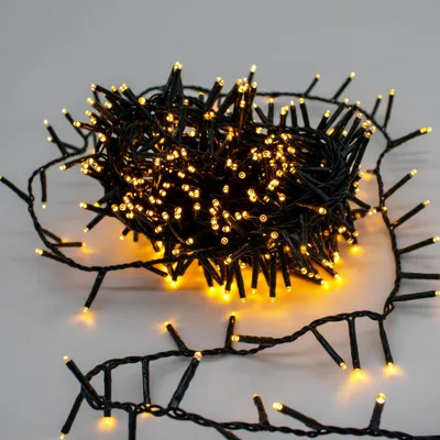 A coiled string of Christmas lights with small yellow LEDs on a light gray background.