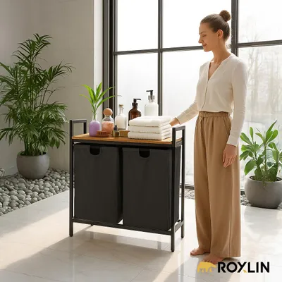 A woman is standing next to a laundry basket in a modern bathroom setting.