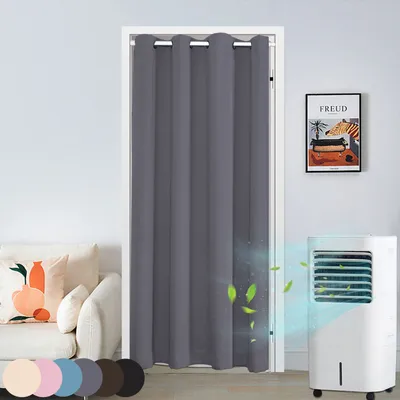 A gray door curtain hanging in a doorway, with a couch and a portable air cooler visible.