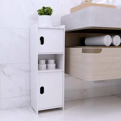 A white bathroom cabinet with two doors and an open shelf, placed on a marble floor next to a marble tiled wall.