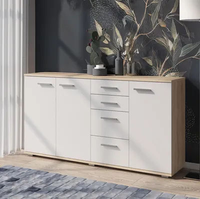 A modern sideboard with white doors and drawers, and a Sonoma oak top, is shown in a room with a patterned wallpaper and a blue rug.