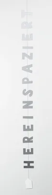 A vertical string of letters spelling out "HEREINSPAZIERT" against a white background.