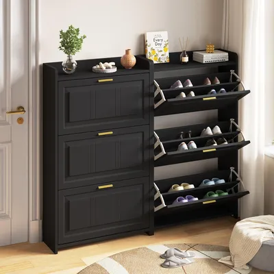 A black shoe cabinet with multiple flip-down doors, placed indoors next to a door and a window.