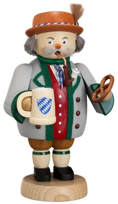 Ein traditioneller Räuchermann in bayerischer Tracht hält einen Maßkrug und eine Brezel in den Händen während er eine Pfeife im Mund hat