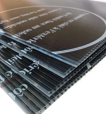 A stack of black corrugated plastic sheets with white text and a circular graphic.