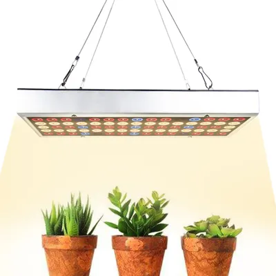 A grow light is shown suspended above three potted plants.