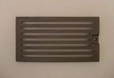 A rectangular cast iron grate with horizontal slots, placed on a light gray background.