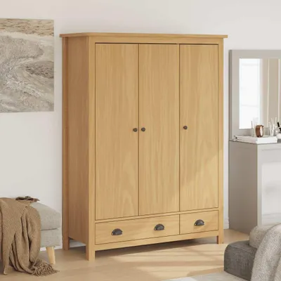 A wooden wardrobe with three doors and two drawers, placed in a room with a painting on the wall and a bench with a blanket.