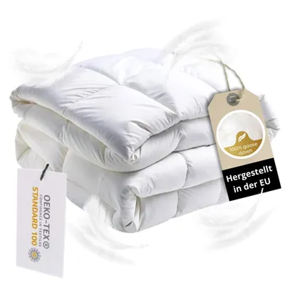 A stack of white duvets with feathers floating around them.