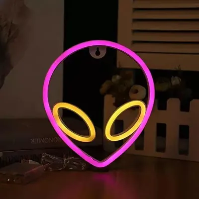 A neon alien head light is displayed on a table.