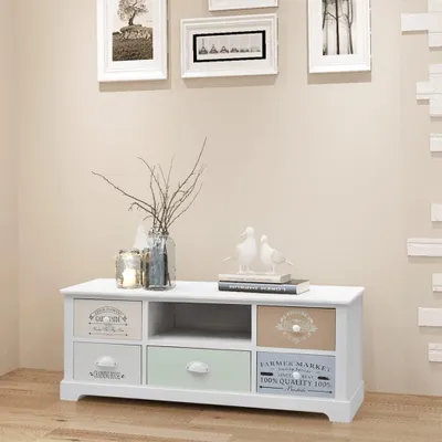 A white TV stand with multiple drawers and an open shelf, decorated with two ceramic doves and a vase of branches.