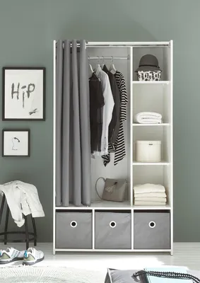 A white wardrobe with clothes hanging inside and items stored in drawers and shelves, set against a gray wall.
