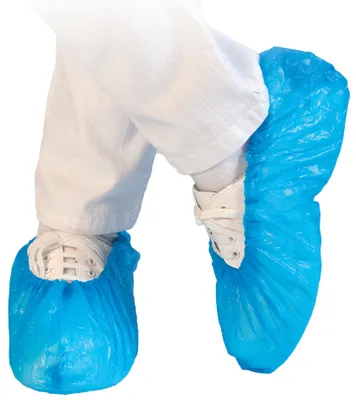 A person wearing white pants and white sneakers covered with blue shoe covers.