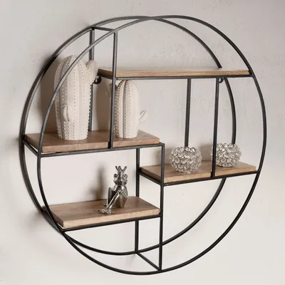 A round, black metal wall shelf with wooden shelves, decorated with two white cactus figures, two clear decorative spheres, and a silver frog figurine.