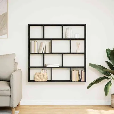 A black, multi-compartment wall shelf filled with books and decorative items, mounted on a white wall next to a sofa and a large potted plant.