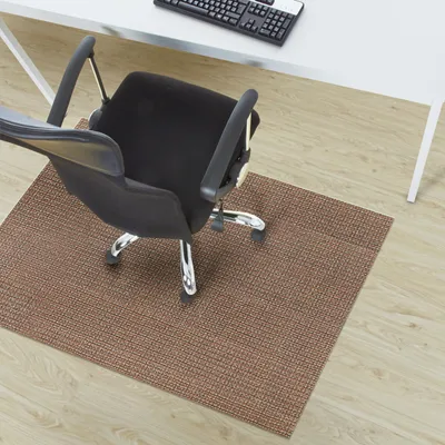 An office chair on a brown floor mat in front of a white desk.