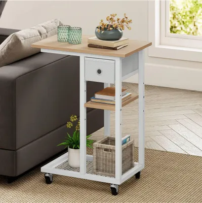 A C-shaped side table with a drawer and shelves is placed next to a sofa, with decorative items on top and a plant and basket on the lower shelves.