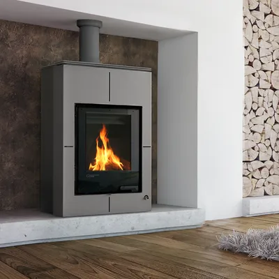 A modern fireplace with a lit fire, set in a living room with a wood-paneled wall and wooden floor.