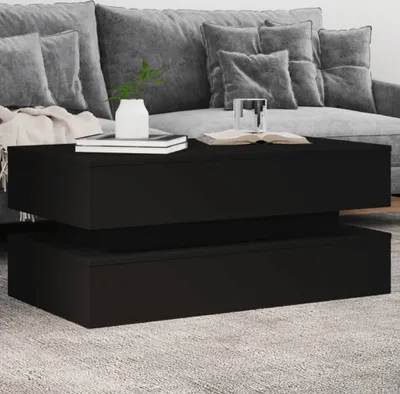 A black coffee table placed on a rug in front of a grey sofa.