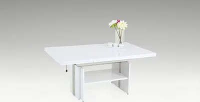 A white coffee table with a vase of flowers and two small cups on top, set against a light gray background.