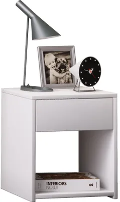 A white nightstand with a lamp, framed photo, and clock on top, and a book on the shelf below.