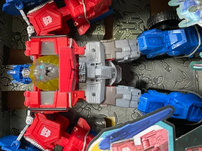 A close-up view of several Transformers toys, including a red and gray robot with a lion's head, and blue robot parts.