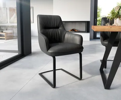 A modern dining room with a black leather chair and a wooden table.