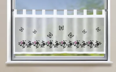 A sheer curtain with a floral and butterfly pattern hanging in a window.