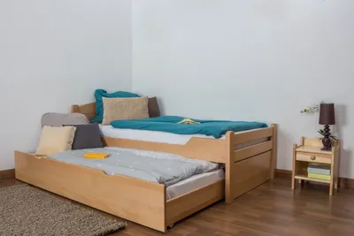 A wooden trundle bed with two mattresses in a room.