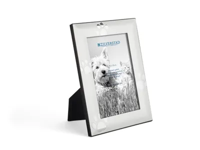 A silver picture frame with paw print decorations, standing on a black easel.