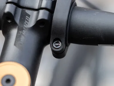 Close-up of a bicycle stem and handlebar clamp with a bolt.