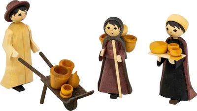 Drei Holzfiguren in traditioneller Kleidung stehen zusammen wobei eine Figur eine Schubkarre mit Geschirr schiebt eine andere einen Krug trägt und die dritte ein Tablett mit Tassen balanciert