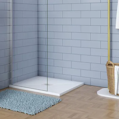 A modern bathroom corner with a shower tray, blue tiled walls, and a wooden floor.