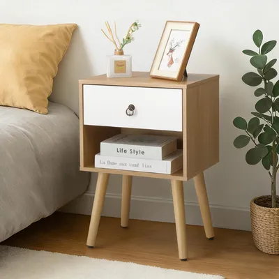 A bedside table with a drawer and an open shelf, placed next to a bed. Decorative items like a picture frame and diffuser are on top.