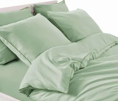 A close-up view of a neatly made bed with light green bedding.