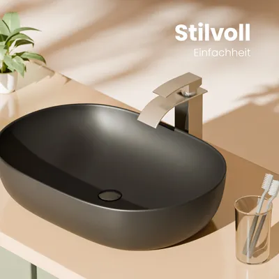 A modern bathroom sink setup with a matte black oval basin, a beige faucet, and a glass holder with toothbrushes.