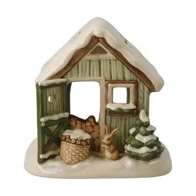 A ceramic winter-themed garden shed decoration with snow, a basket of firewood, a rabbit, and a Christmas tree.