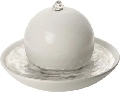 A white spherical fountain sits in a white bowl filled with water.