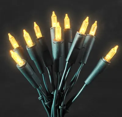 A close-up shot of a string of yellow LED lights with green wires against a dark background.