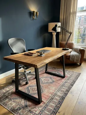 Der Holztisch mit schwarzen Trapezbeinen kombiniert mit einem ergonomischen Bürostuhl vor einem großen Fenster, eine ideale Einrichtung für das produktive Homeoffice._#sku_SAFWL7.263#