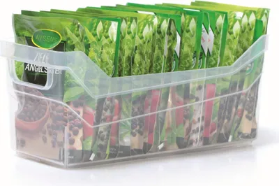 A clear plastic storage container filled with packets of seeds.
