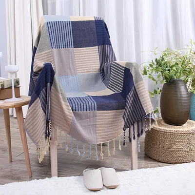 A blanket draped over a chair with slippers on the floor and plants in the background.