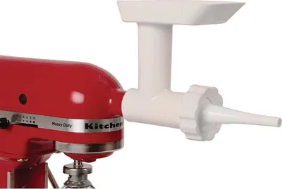 A red KitchenAid stand mixer with a white meat grinder attachment.