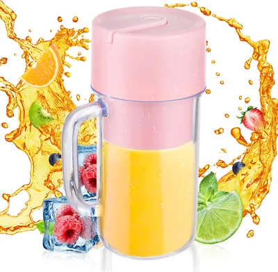 A portable blender filled with yellow juice, surrounded by splashes of orange juice and various fruits like strawberries, blueberries, raspberries, kiwi, and lime.