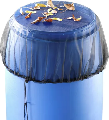 A blue rain barrel with a black mesh cover on top, littered with leaves.