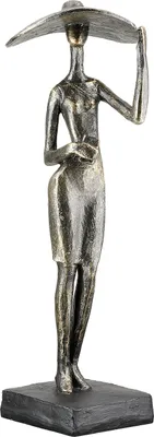 A bronze-colored sculpture of a woman wearing a wide-brimmed hat and a dress, standing on a dark gray base.