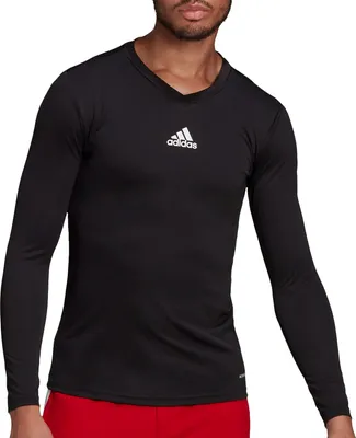 A man wearing a black long-sleeved Adidas shirt and red shorts.