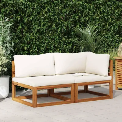 An outdoor sofa set with cream cushions is placed on a tiled patio in front of a lush green hedge.