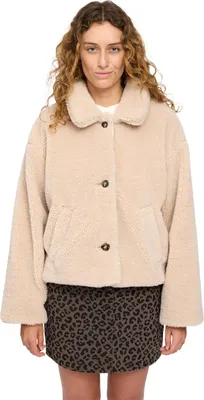 A woman wearing a beige faux fur jacket and a leopard print skirt.